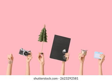 Journalist's female hands with Christmas fir decorations, notebook, camera and badge on pink background