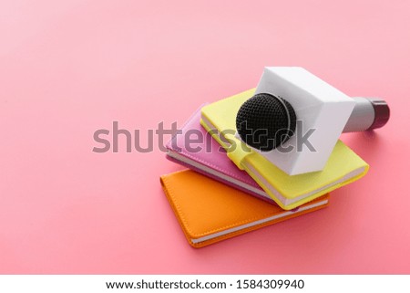 Journalist's microphone and notebooks on color background