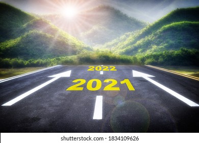 Journey To New Year 2021 To 2022 On Asphalt Road With White Arrow And Mountain Nature Background. Future Ahead Concept And Beginning With Sunrise Idea