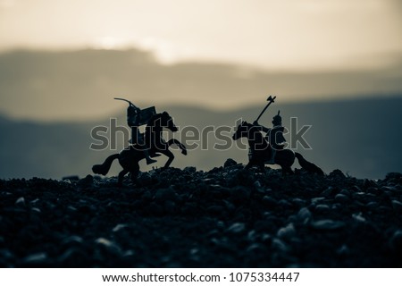 Joust between two knights on horseback. Sunset on background.