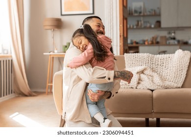 Joy Of Fatherhood. Loving Asian Dad Embracing His Cute Little Baby Daughter, Expressing Care And Love Posing In Modern Living Room At Home. Family Happiness, Cute Moments Concept - Powered by Shutterstock