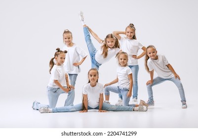 Joy, fun and happiness. Portrait of happy, active little girls, sportive kids in casual clothes dancing isolated on white studio background. Concept of music, fashion, art, childhood, hobby. - Powered by Shutterstock