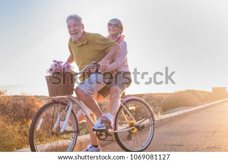 joy and happiness for adult married couple start and have fun traveling on the same bike in outdoor activity with sun backlight on the background. clear and bright image for smile and laugh people. 