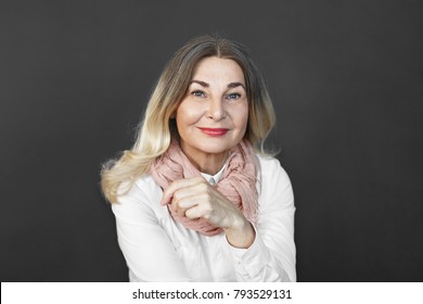 Joy, happiness and positiveness. Joyful charming elderly woman in good mood posing isolated at studio wall wearing stylish scraf over white blouse, looking at camera with positive happy smile