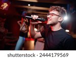 Joy and music. Happy young man is singing in karaoke nightclub