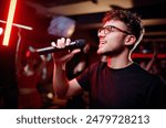 Joy and music. Happy young man is singing in karaoke nightclub