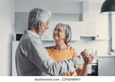 Joyful active old retired romantic couple dancing laughing in living room, happy middle aged wife and elder husband having fun at home, smiling senior family grandparents relaxing bonding together - Powered by Shutterstock