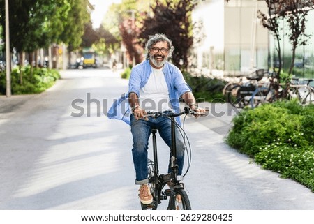 Joyful active senior man doing healthy exercise riding bicycle in the city