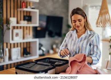 Joyful Adult Woman, Picking Up Her Clothes From The Table, Packing Into The Coffer.