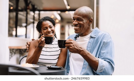 A joyful African American couple share a laugh while sipping coffee in a cozy cafe setting, radiating happiness and warmth. - Powered by Shutterstock