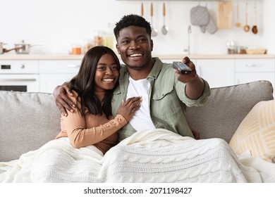 Joyful African American Couple Watching TV Together At Home, Laughing And Bonding, Copy Space. Happy Young Black Man And Woman Having Fun Together On Weekend, Love And Relationships Concept