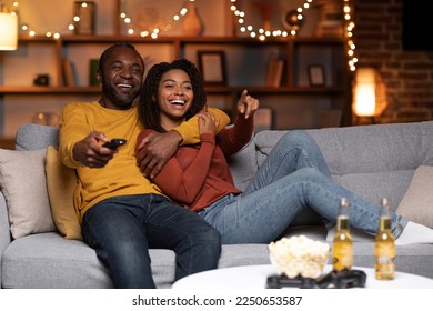 Joyful african american couple watching TV together at home, laughing, bonding, copy space. Happy black man and woman having fun together during winter holidays, love and relationships concept - Powered by Shutterstock