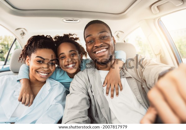 Joyful African\
American Family Hugging Sitting In Car During Summer Road Trip.\
Parents And Daughter Posing In New Auto Smiling To Camera.\
Transportation, New Automobile\
Concept