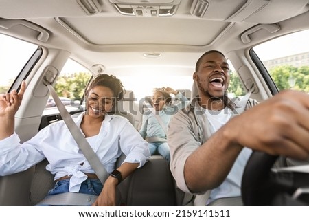 Joyful African American Family Riding New Car Singing And Having Fun During Summer Road Trip. Parents And Daughter Traveling By Auto On Weekend. Transportation. Selective Focus