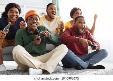 Joyful african american friends playing video games at home