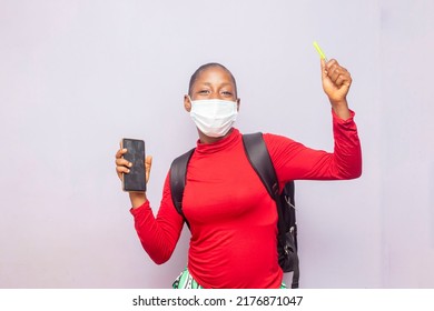 Joyful African College Student Smiling In Mask , Black Teen Holding Mobile Phone And Pen Whilst Carrying Backpack