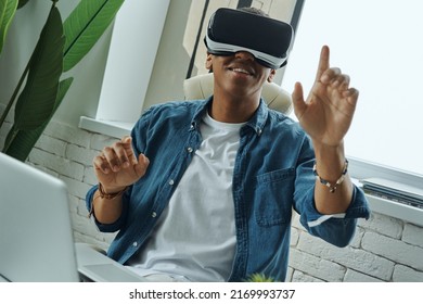 Joyful African Man Wearing Virtual Reality Glasses While Sitting At Working Place