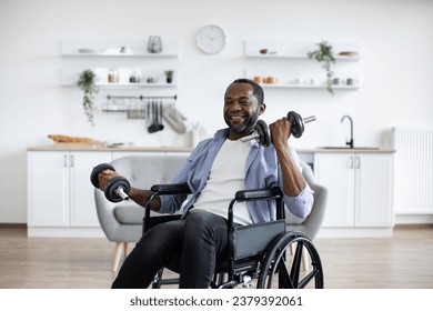 Joyful african person with physical disability holding dumbbells in arms during strength training at home. Active wheelchair user building muscles while experimenting with workout routine. - Powered by Shutterstock