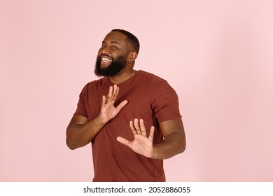 Joyful African-American guy with beard in brown t-shirt holds hands in front refusing an offer on studio pink background - Shutterstock ID 2052886055