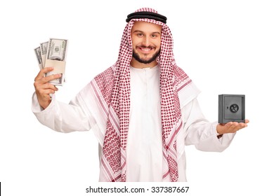 Joyful Arab holding few stacks of money in one hand and a small metal safe in the other isolated on white background