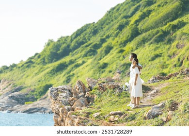 Joyful Asian couple shares romantic moment outdoors, surrounded by scenic mountains and the ocean. Their love and happiness shine through in this serene natural for beautiful wedding day. - Powered by Shutterstock