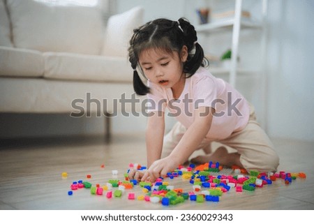 Joyful Asian girl happy and smiling playing colorful toy block, sitting on the living room floor, creatively playing with block, building colorful structures creativity imagine. Learning education.