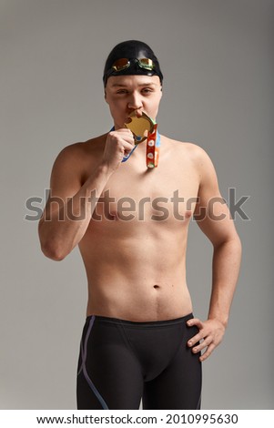 Joyful athlete swimmer kissing the won medal positive emotions, joy of victory, success concept.
