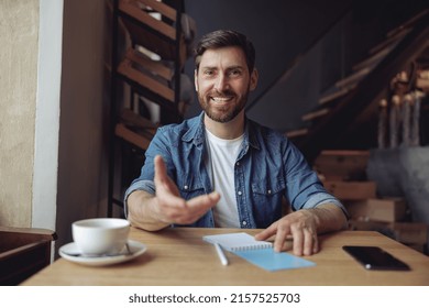 Joyful Attractive Man Reaching For Camera With Hand. Coffee Time In Cafe. Portrait. Give Me Gesture.