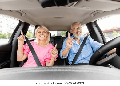 Joyful attractive senior man and woman riding auto, listening to music and singing songs, shot from dashboard. Happy elderly couple friends have car ride, enjoying nice adventure, have fun - Powered by Shutterstock