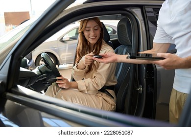 Joyful automobile buyer getting car key fob from salesperson