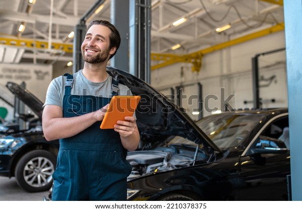 Joyful automotive technician standing at the
service station