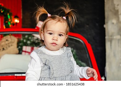 Joyful Baby Looking At Camera Sitting On Red Christmas Car In The Living Room At Home. Merry Christmas And Happy Holidays! 