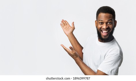 Joyful Bearded Black Man Gesturing Showing Free Space For Text Aside Standing In Studio Over White Background. Advertisement Banner. Look At This, Great Offer Concept. Panorama - Shutterstock ID 1896399787