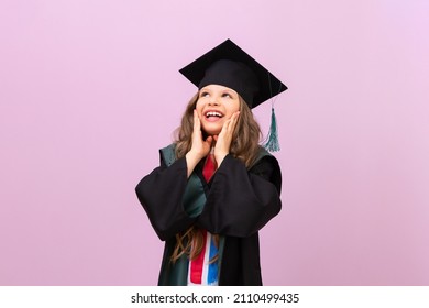 A joyful beautiful graduate looks up. a schoolgirl in a graduate's robe and a master's hat. the child is happy to receive an education in another country. - Powered by Shutterstock