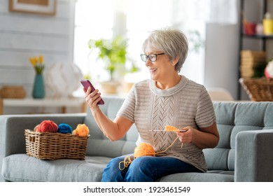 Joyful beautiful senior woman is using smartphone sitting on the sofa at home. - Powered by Shutterstock