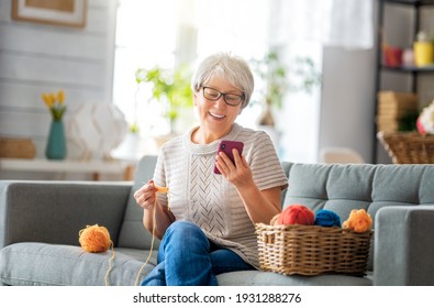 Joyful beautiful senior woman is using smartphone sitting on the sofa at home. - Powered by Shutterstock