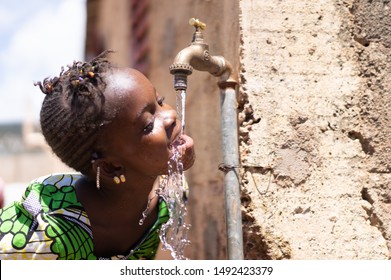 Joyful Black Child Drinks Fresh Water From A Tap