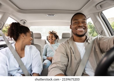 Joyful Black Family Driving New Car Having Ride In City. Parents And Daughter Sitting In Automobile Enjoying Road Trip On Vacation. Transportation Concept. Selective Focus