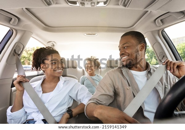 Joyful\
Black Family Riding New Car Enjoying Summer Road Trip Together.\
Parents And Little Daughter Sitting In Automobile, Putting On Seat\
Belts For Safety. Transportation, New Auto\
Concept