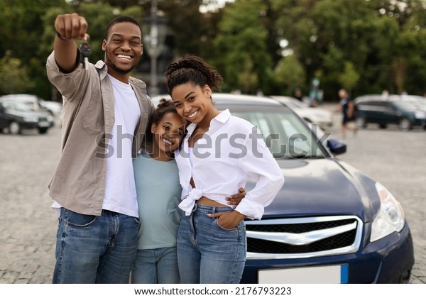 Joyful Black\
Family Showing New Car Key Posing Standing Near Luxury Auto\
Outdoor, Smiling To Camera. Parents And Daughter Celebrating Buying\
Vehicle. Automobile Leasing And\
Ownership