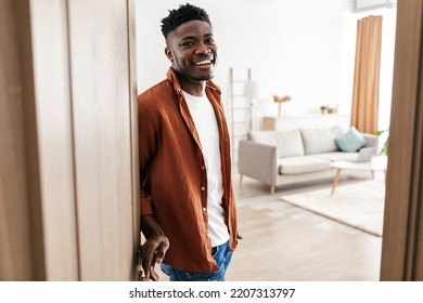 Joyful Black Guy Opening Door Meeting You Smiling To Camera Standing At Home. Male Welcoming You To His New Apartment. Great Real Estate Offer Concept. Selective Focus