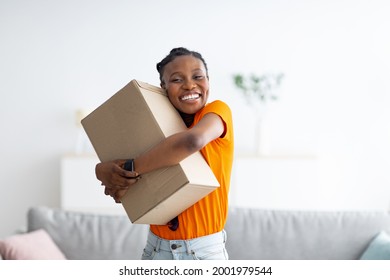 Joyful black woman embracing carton parcel, receiving desired delivery, getting online order at home. Cheerful African American lady satisfied with her internet purchase, hugging package - Shutterstock ID 2001979544