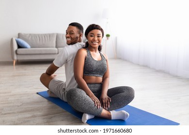 Joyful black woman sitting back to back with her boyfriend in lotus pose, having morning yoga practice at home. Happy African American couple exercising together during covid isolation - Powered by Shutterstock