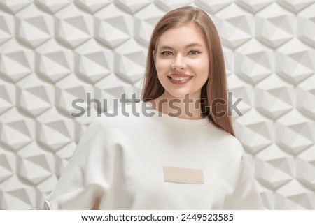 Joyful blonde girl posing in a loose white jumper on a white geometric studio background. Women's fashion. Happy people. 