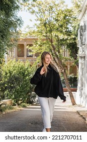 Joyful And Blonde Woman In Trendy Outfit Walking On Street In Turkey