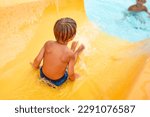 Joyful boy descends from the water slide in the water park, children