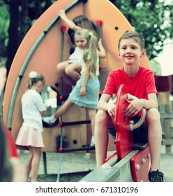 joyful  boy in elementary school age riding toy on children's playground - Shutterstock ID 671310196