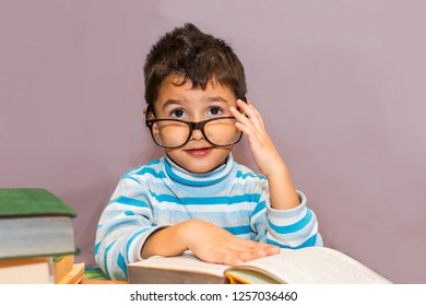 joyful boy with glasses at the study table with books