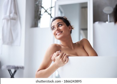 Joyful brunette woman is spending good time while having bath during spa day at home. Concept of beauty, self-care, cosmetics