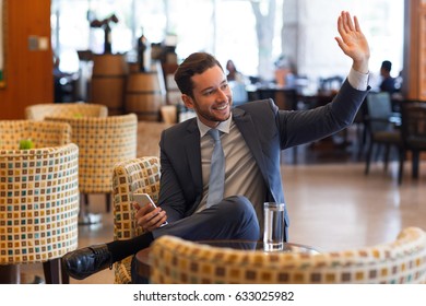 Joyful Business Man Waving To Someone In Cafe